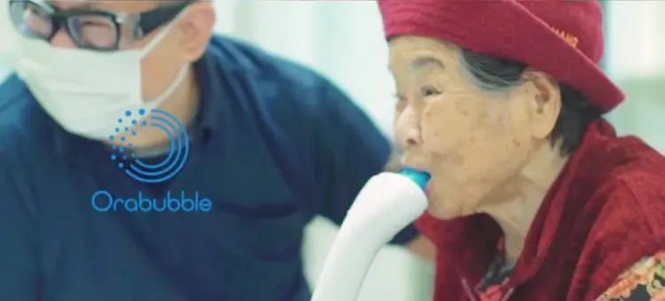 高齢者がオーラバブルを口にくわえて口腔洗浄に使用している様子の写真